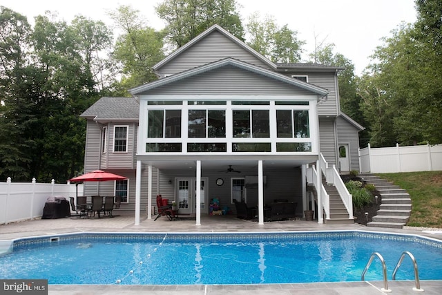 rear view of house with a fenced in pool, a patio area, fence, and stairs