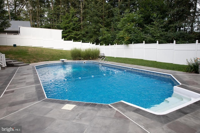 view of swimming pool featuring a fenced backyard, a fenced in pool, a lawn, and a patio