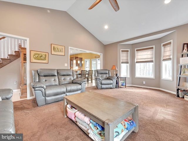 living area featuring a ceiling fan, carpet, high vaulted ceiling, and stairs