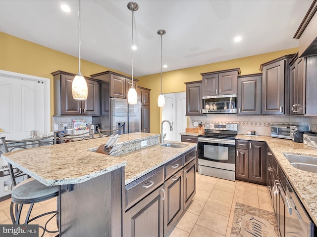 kitchen featuring appliances with stainless steel finishes, a breakfast bar area, a sink, and dark brown cabinets