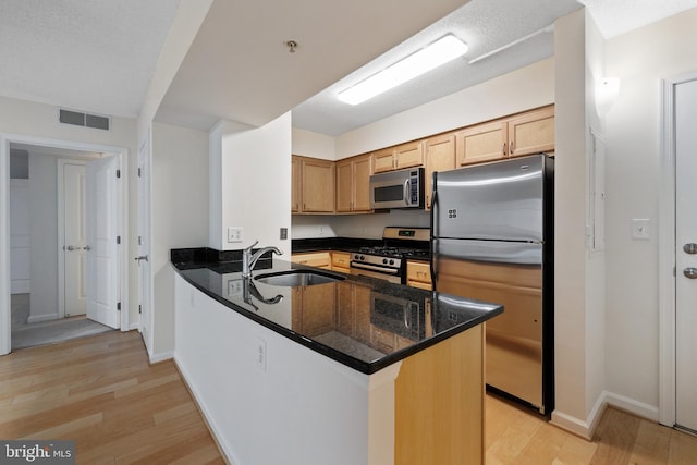 kitchen featuring stainless steel appliances, a peninsula, a sink, visible vents, and light wood-type flooring