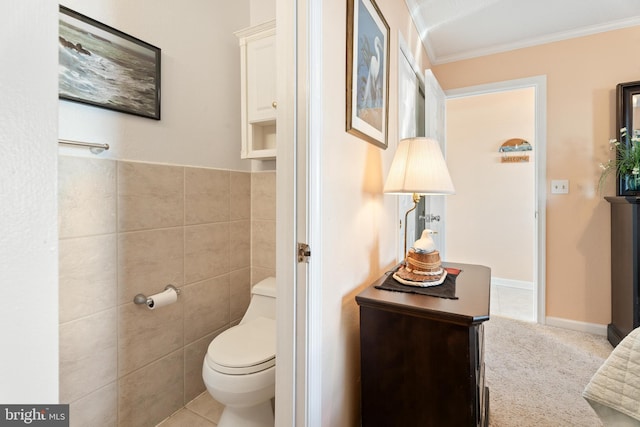 bathroom with toilet, tile patterned flooring, tile walls, and crown molding