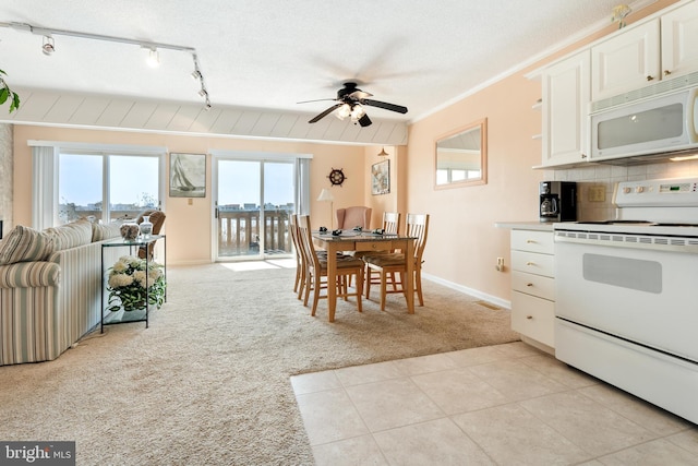 dining area featuring light tile patterned floors, a ceiling fan, light colored carpet, rail lighting, and crown molding