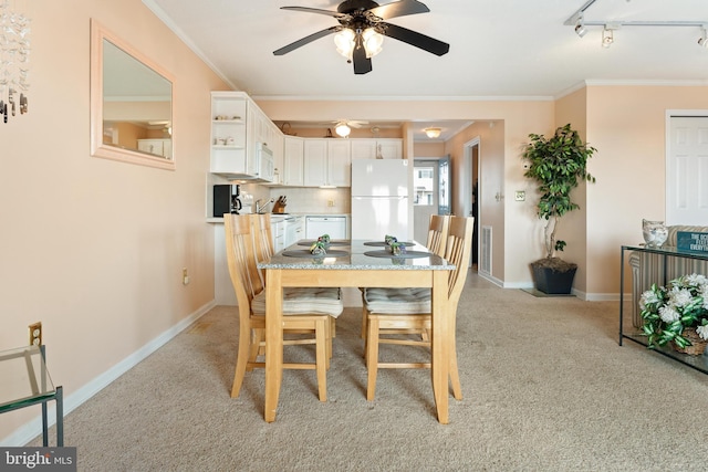 dining space with rail lighting, baseboards, ornamental molding, and light colored carpet