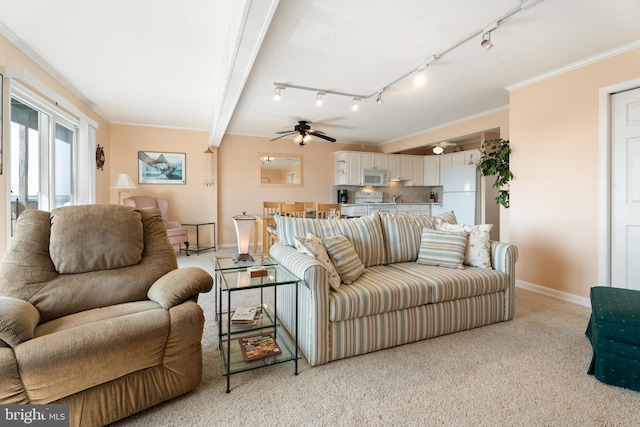 living area with ornamental molding, beamed ceiling, a ceiling fan, and baseboards