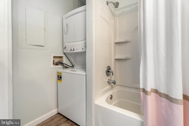 bathroom with stacked washer / dryer, wood finished floors, baseboards, electric panel, and shower / tub combo with curtain