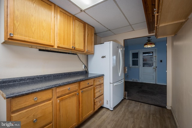 kitchen with visible vents, dark countertops, wood finished floors, freestanding refrigerator, and a paneled ceiling