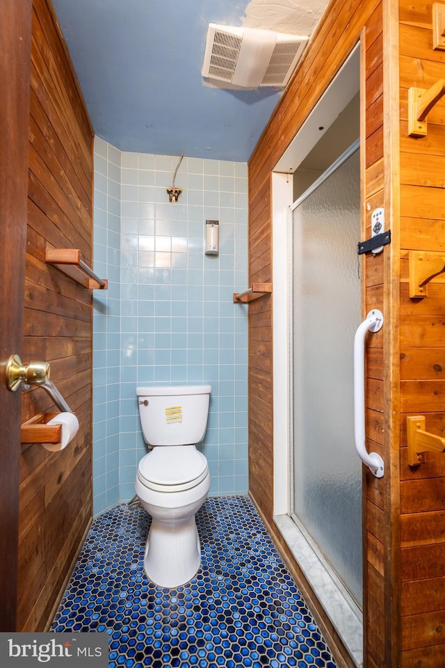 full bath with toilet, a shower stall, visible vents, and tile walls