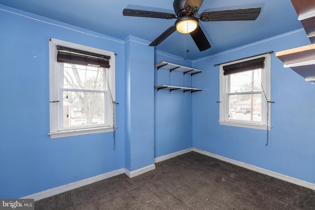 carpeted empty room with ceiling fan and baseboards