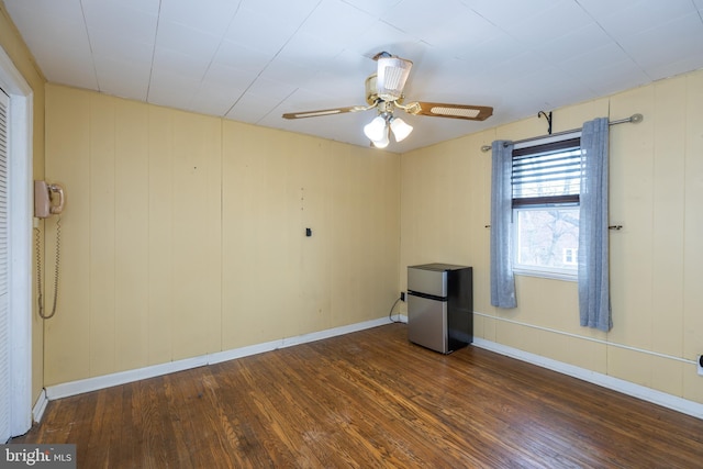 empty room featuring baseboards, ceiling fan, and hardwood / wood-style floors