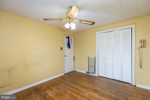 unfurnished bedroom featuring ceiling fan, a closet, baseboards, and wood finished floors