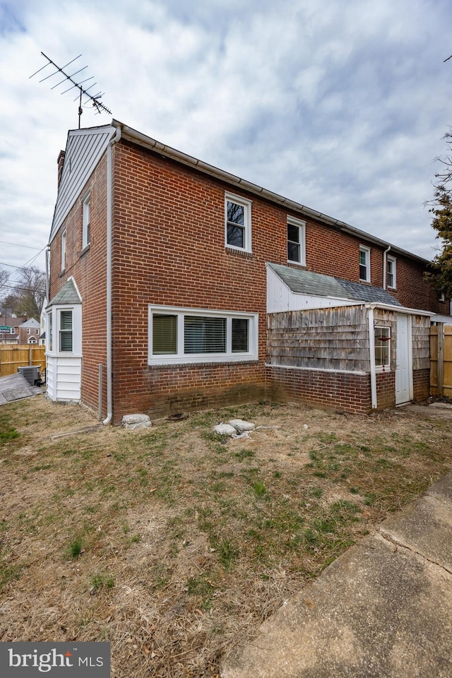 back of property featuring brick siding and fence