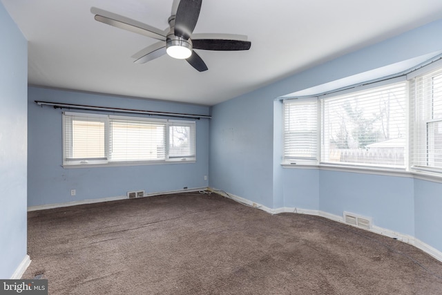 carpeted spare room with ceiling fan, visible vents, and baseboards