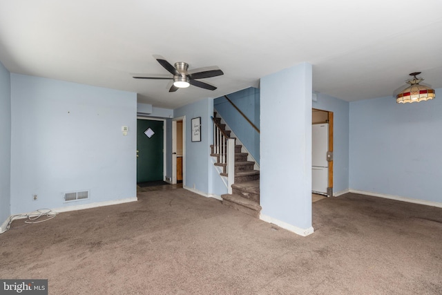 carpeted empty room with stairs, a ceiling fan, visible vents, and baseboards