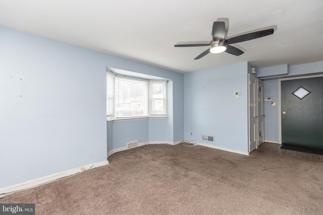 carpeted spare room featuring a ceiling fan, visible vents, and baseboards