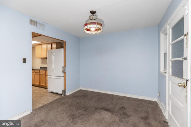 empty room with baseboards, visible vents, and light colored carpet