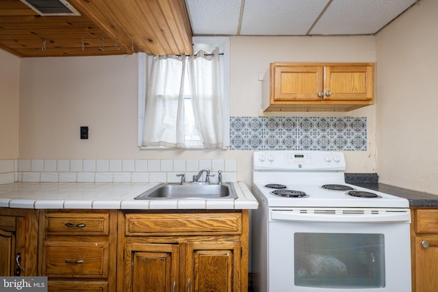 kitchen featuring a sink, visible vents, backsplash, brown cabinets, and white range with electric cooktop