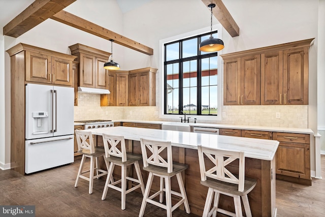 kitchen with dark wood-type flooring, a center island, high end white fridge, beam ceiling, and brown cabinets