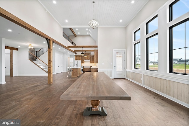 unfurnished living room featuring stairs, ornamental molding, dark wood-style floors, and an inviting chandelier