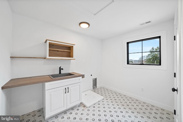 laundry area with cabinet space, visible vents, hookup for an electric dryer, a sink, and baseboards