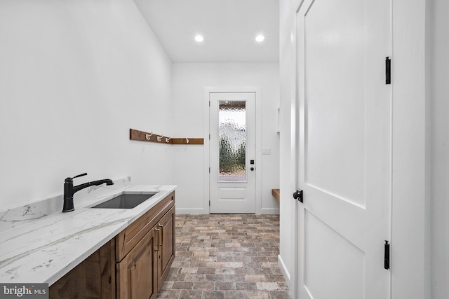 clothes washing area featuring baseboards, a sink, and recessed lighting