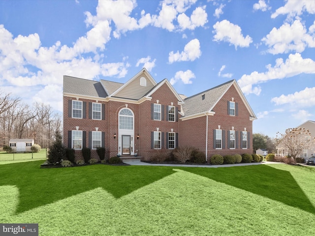 view of front facade featuring brick siding, a front lawn, and fence