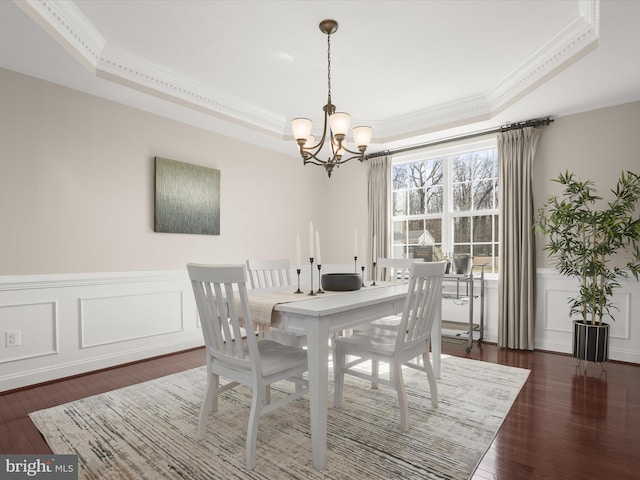 dining area with a chandelier, dark wood-style floors, crown molding, and a tray ceiling