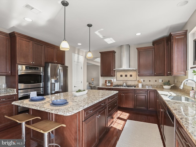 kitchen featuring visible vents, dark wood finished floors, a sink, appliances with stainless steel finishes, and wall chimney range hood