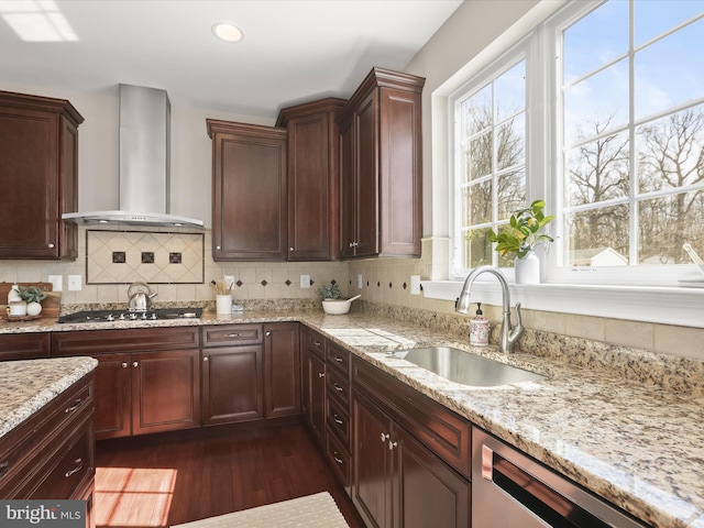 kitchen with a sink, tasteful backsplash, appliances with stainless steel finishes, wall chimney range hood, and a healthy amount of sunlight