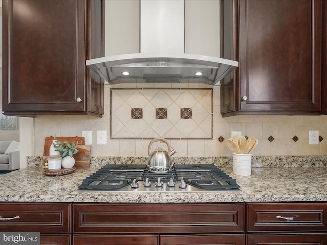 kitchen featuring stainless steel gas cooktop, dark brown cabinets, tasteful backsplash, and exhaust hood