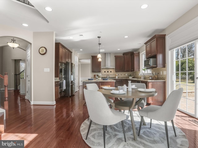 dining room with arched walkways, recessed lighting, baseboards, and dark wood-style flooring