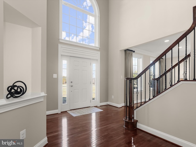 foyer featuring stairway, baseboards, a high ceiling, and hardwood / wood-style floors