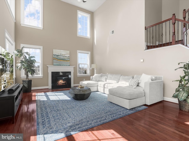 living room with visible vents, a glass covered fireplace, wood finished floors, stairway, and baseboards