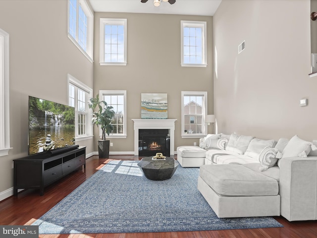 living room featuring a fireplace with flush hearth, wood finished floors, and baseboards