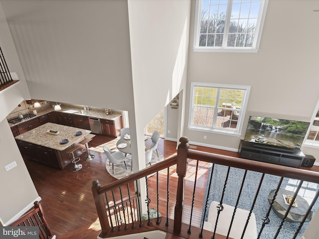 stairway with a high ceiling, wood finished floors, and baseboards