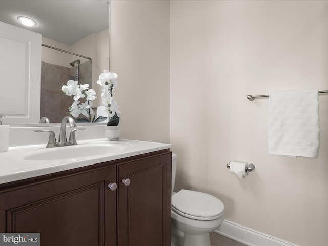 bathroom featuring tile patterned flooring, baseboards, toilet, vanity, and a shower