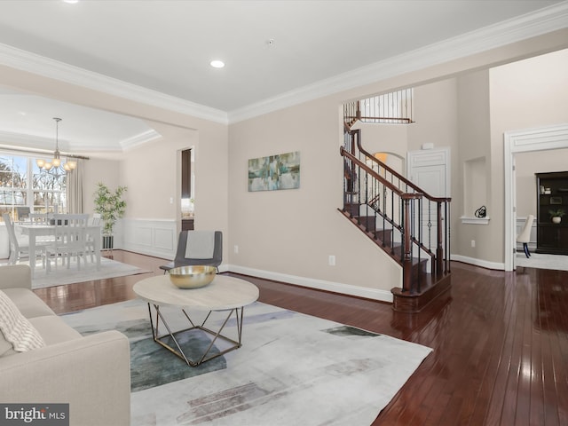 living area with ornamental molding, hardwood / wood-style floors, an inviting chandelier, baseboards, and stairs