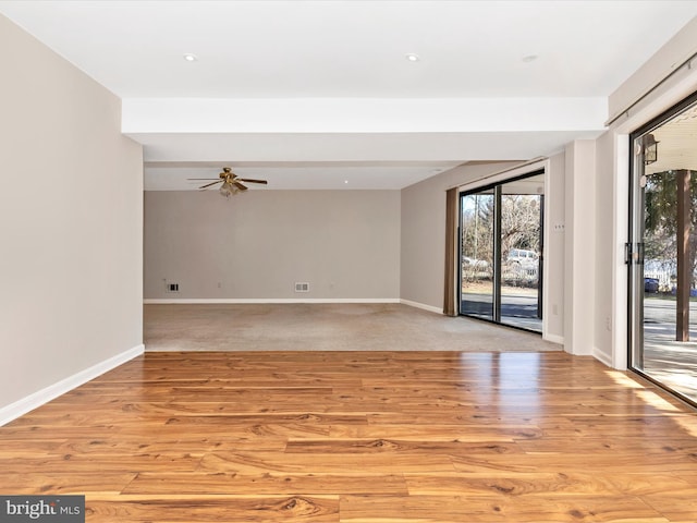 empty room with plenty of natural light, light wood-style flooring, and baseboards