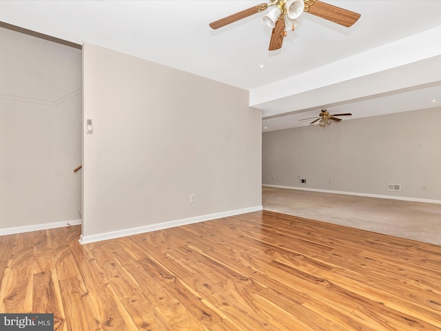 spare room featuring light wood-style floors, visible vents, baseboards, and a ceiling fan