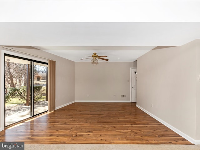 spare room featuring a ceiling fan, visible vents, baseboards, and wood finished floors