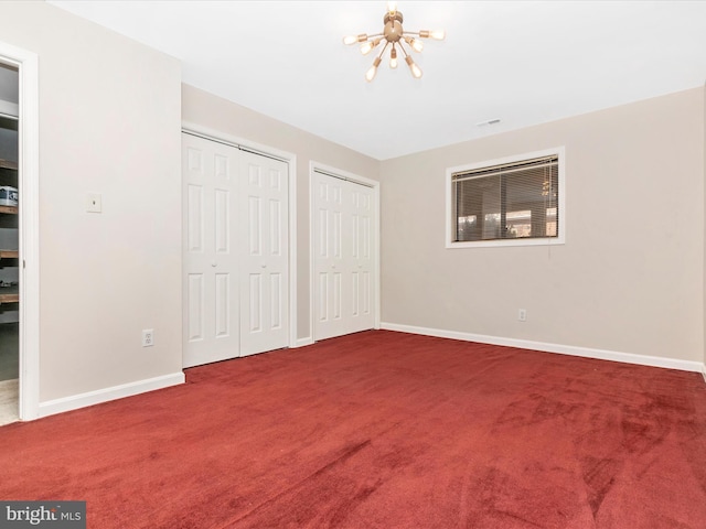 unfurnished bedroom with a chandelier, carpet floors, baseboards, and multiple closets