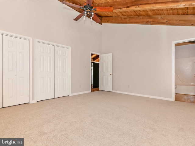 unfurnished bedroom featuring carpet floors, multiple closets, wood ceiling, beamed ceiling, and baseboards