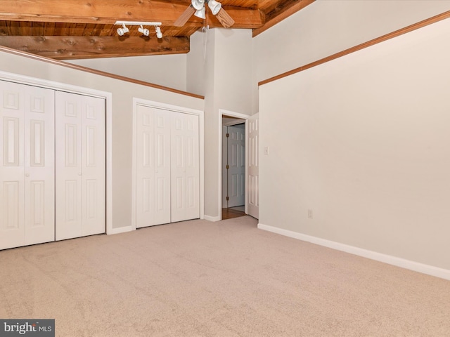 unfurnished bedroom featuring carpet floors, wooden ceiling, baseboards, and two closets