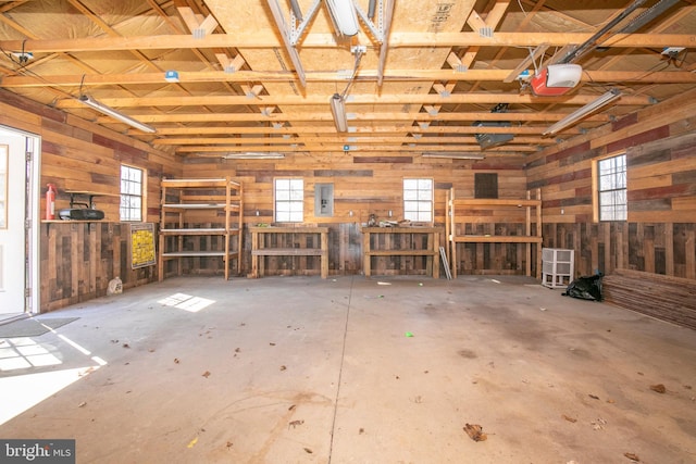 garage featuring wood walls, electric panel, and a garage door opener