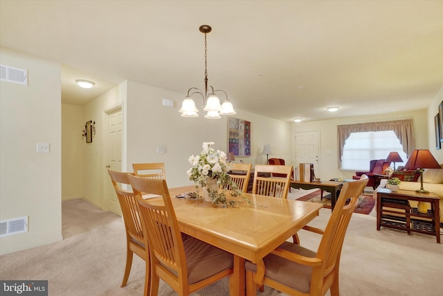 dining space featuring visible vents, light carpet, and an inviting chandelier