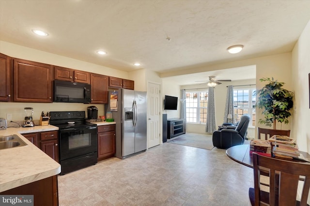 kitchen featuring recessed lighting, a sink, open floor plan, light countertops, and black appliances