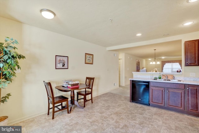 kitchen featuring a peninsula, a sink, black dishwasher, light countertops, and decorative light fixtures