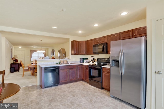 kitchen with a peninsula, a sink, light countertops, black appliances, and decorative light fixtures