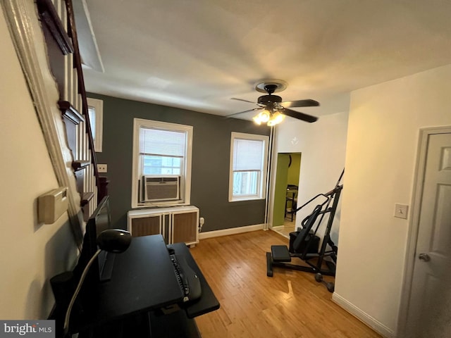 exercise room featuring cooling unit, baseboards, light wood-style flooring, and radiator heating unit