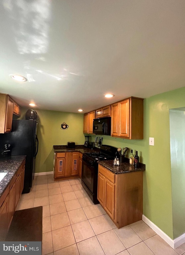 kitchen with light tile patterned floors, black appliances, brown cabinetry, and baseboards